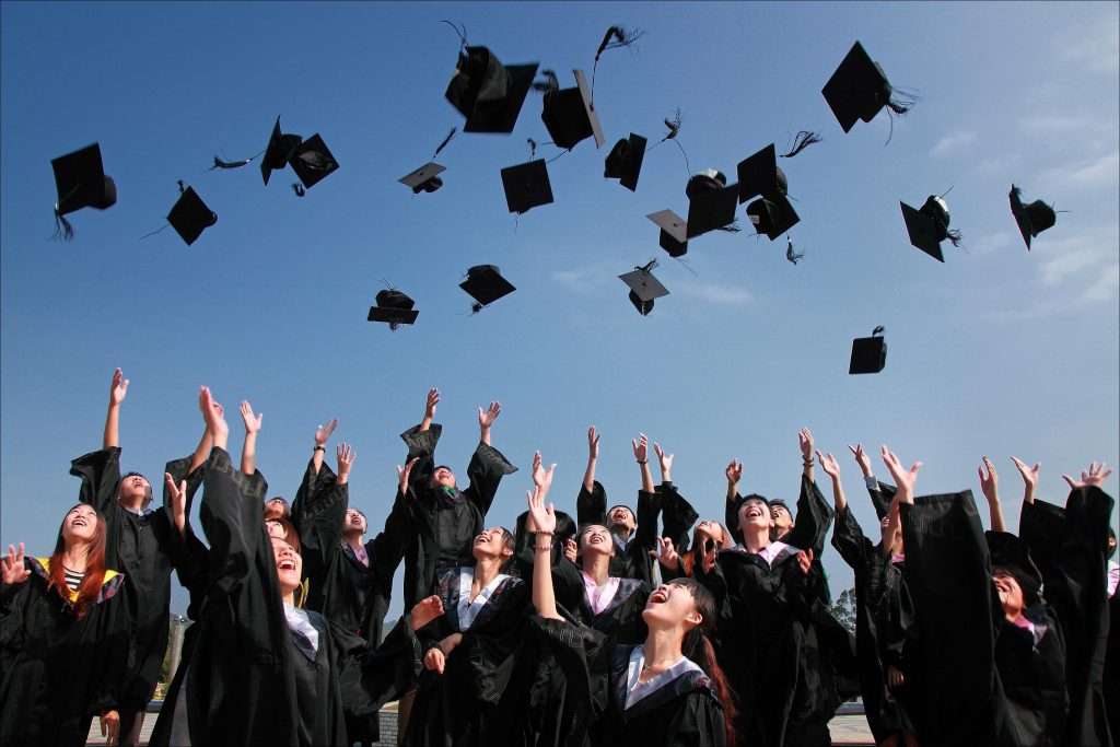 Graduating students in caps and gowns throwing their hats into the air.