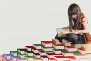 Girl reading while sitting on a stack of books