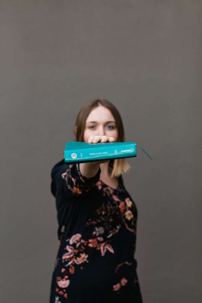 Girl hodling out a book.