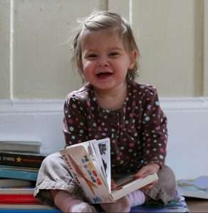 Female baby reading a picture book.