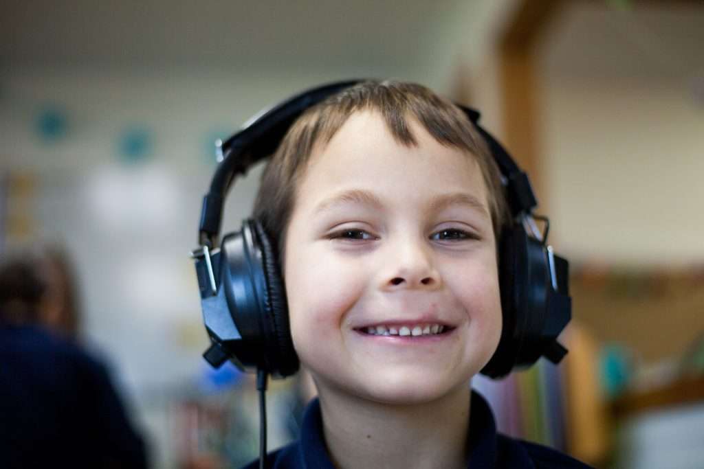 Smiling, young boy with headphones.
