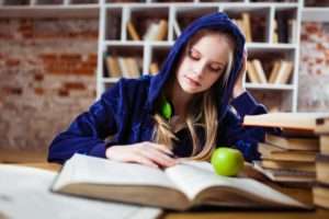 Teen girl in a velvet hoodie reading a book.