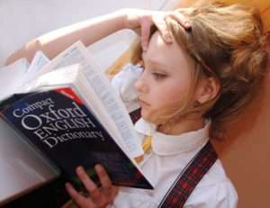Young female reading an Oxford Dictionary to learn new words.
