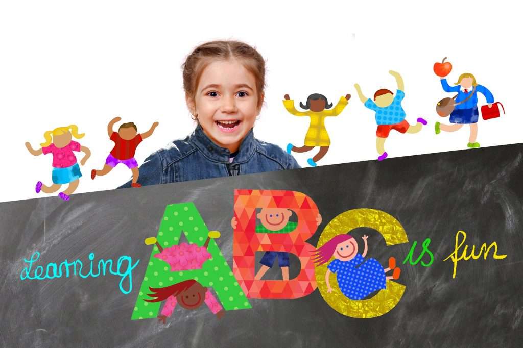 Smiling young girl with the words learning ABC is fun on a sign in front of her. Cartoon children play in the background